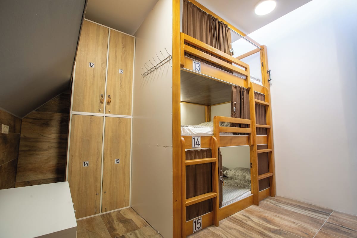 A dormitory room with bunk beds, wooden lockers, and a tiled floor.