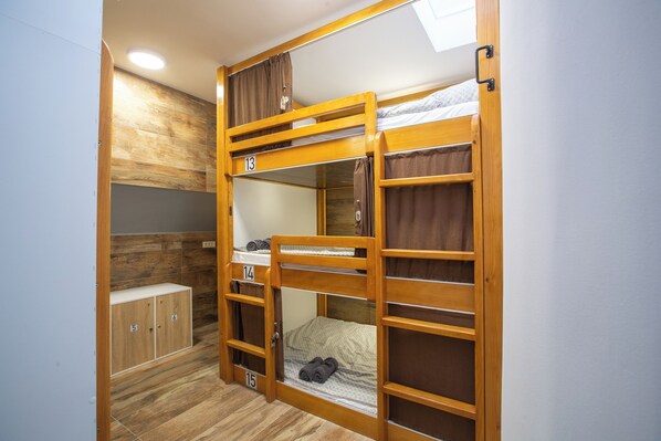 A bunk bed room with wooden bunk beds, a small desk, and a wardrobe with numbered compartments. - AISHA Hostel (Ljubljana)