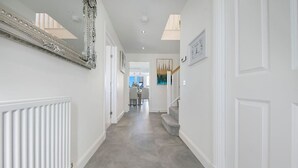 A hallway with a radiator, a staircase, and a dining area in the background. - Fern Place Villa  | Grampian Lettings Ltd (Aberdeen City)