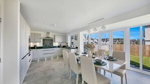 A modern kitchen with a dining area, large windows, and a view of the backyard. - Fern Place Villa  | Grampian Lettings Ltd (Aberdeen City)
