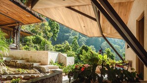 A covered outdoor area with stone steps, a wooden structure, and lush greenery. - Arbórea Villas (Ciudad Cortés)
