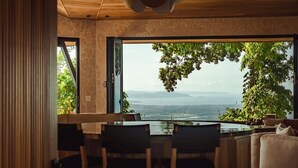 A modern dining area with a view of a lake and mountains. - Arbórea Villas (Ciudad Cortés)