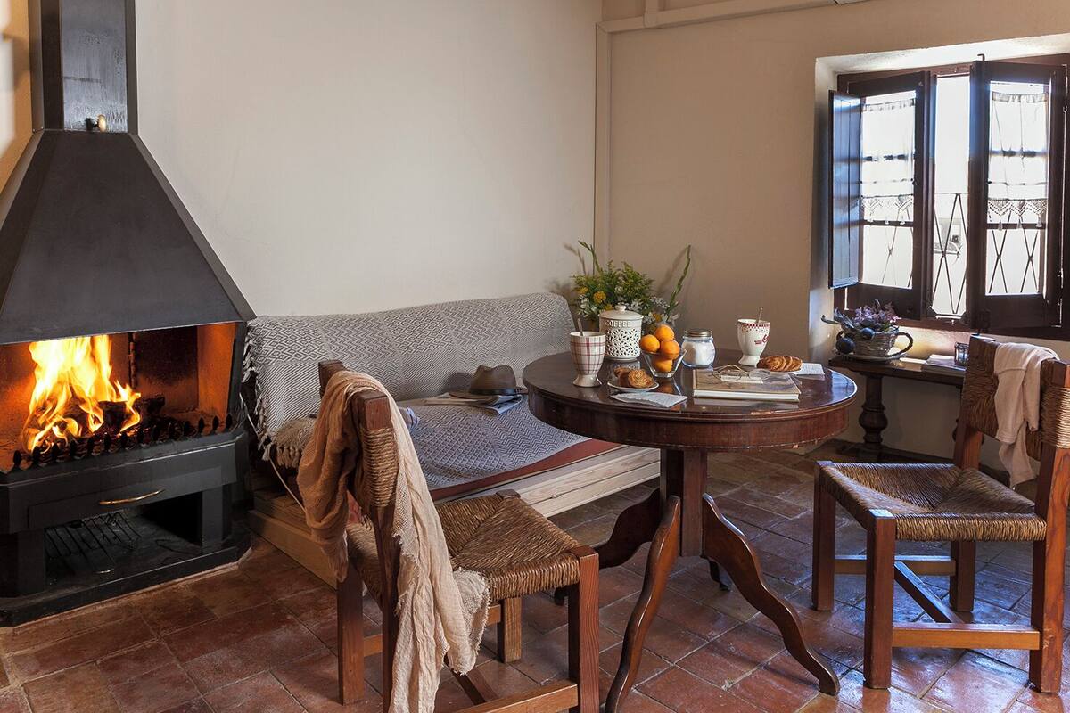 A cozy living room with a fireplace, a round wooden table, and a comfortable seating area.