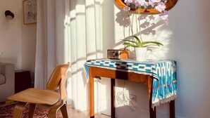 Une pièce avec un bureau en bois, une chaise, un grand miroir et une orchidée en pot.