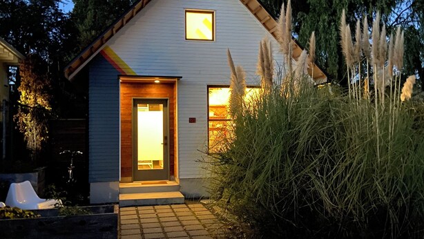Une maison moderne à la façade bleu clair, avec le numéro « 359 » bien visible sur la porte et une petite fenêtre au-dessus de la porte.
