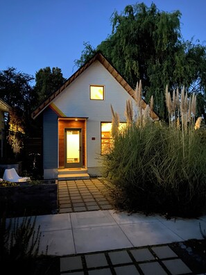 A modern house with a light blue exterior, a visible number '359' on the door, and a small window above the door.