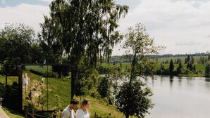 Un sentier longeant un lac, avec une clôture, un arbre et une personne qui marche.