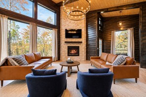A cozy living room with leather sofas, a fireplace, and large windows.