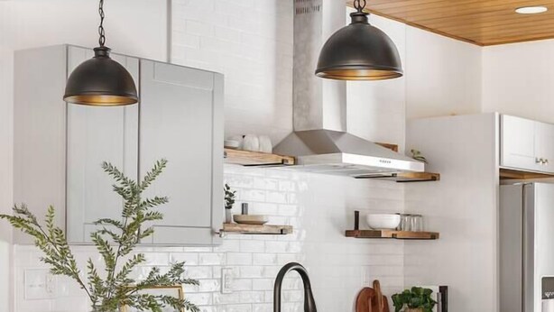 Eine moderne Küche mit Kochinsel, Barhocker, Pendelleuchten und einem Edelstahl-Kühlschrank.
