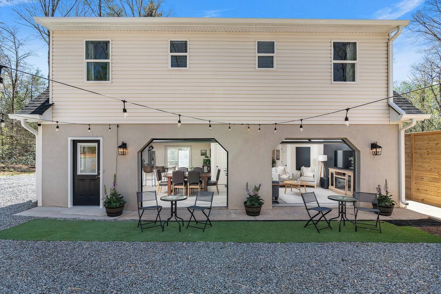 A two-story house with a covered patio area featuring outdoor seating and string lights.