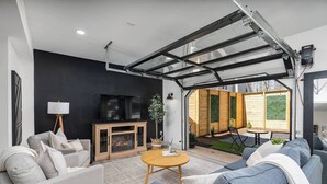 Ein modernes Wohnzimmer mit Kamin, Fernseher und einer Terrassenanlage mit Tisch und Stühlen.
