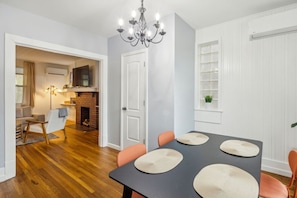 A dining area with a table set for four, a chandelier, and a view into a living room with a fireplace.
