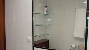 Un baño con lavamanos, espejo y repisas de vidrio.