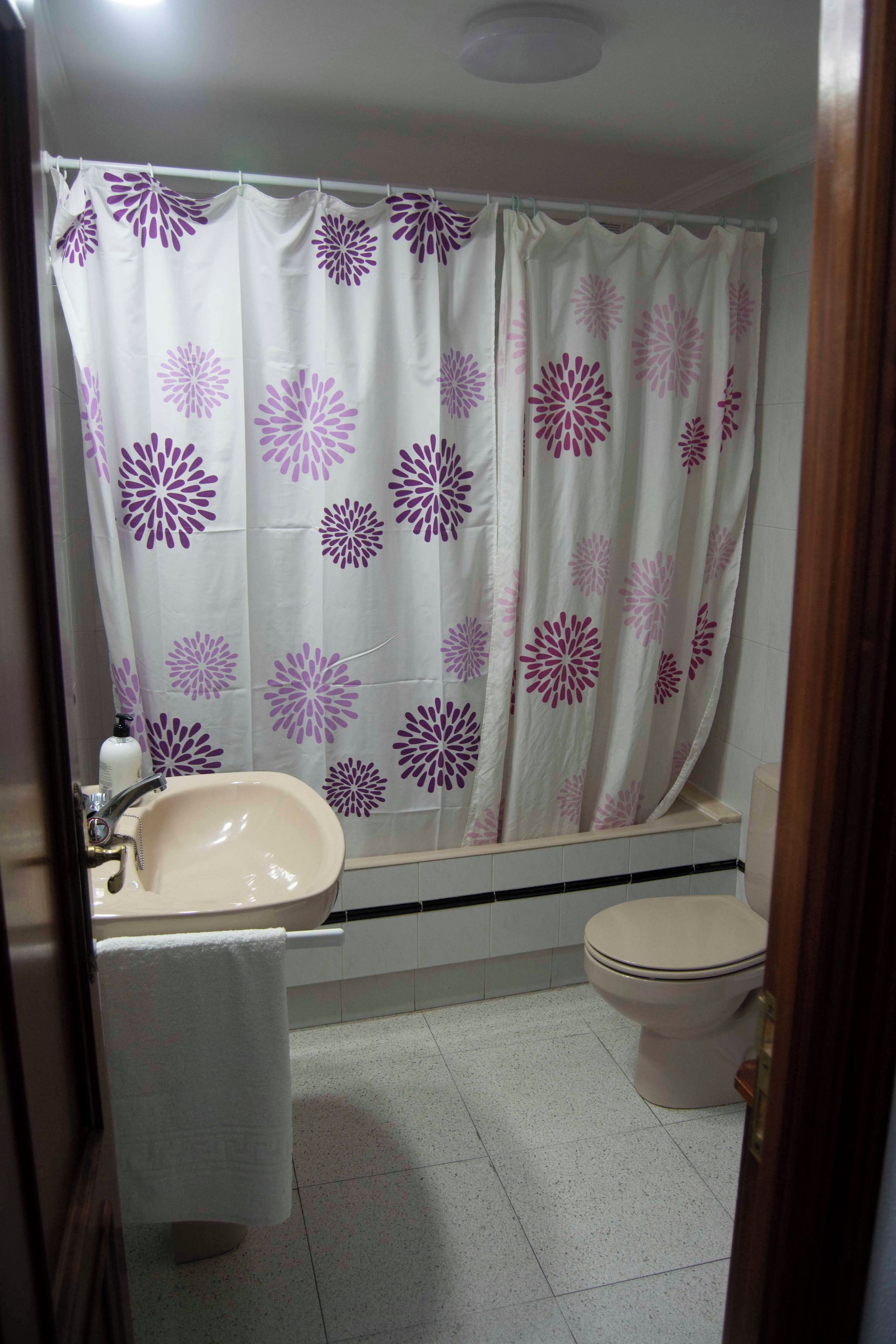 A bathroom with a shower curtain, sink, and toilet.