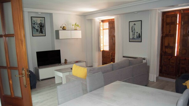 Una sala de estar con un sofá gris, un televisor de pantalla plana y una mesa de centro.