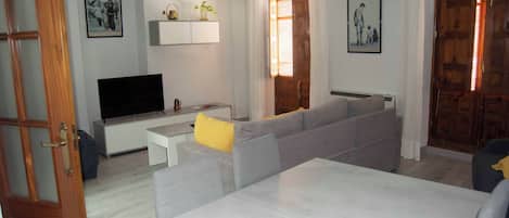 Un salon avec un canapé gris, un téléviseur à écran plat et une table basse.