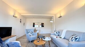 A modern living room with a sofa, armchair, coffee table, and a TV. - Venezia Dream Stay by Ca-sa Check (Mestre)