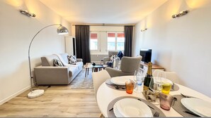 A modern living room with a sofa, dining table set for two, and a television in the background. - Venezia Dream Stay by Ca-sa Check (Mestre)