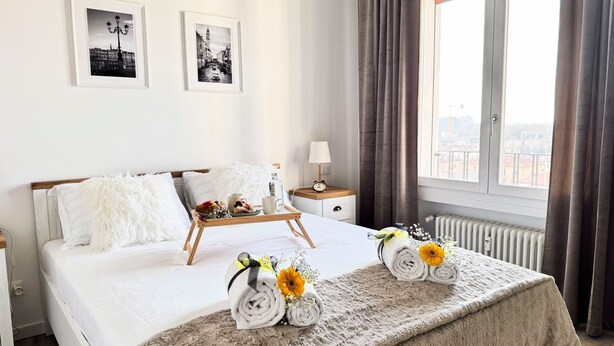 A hotel room with a bed, a bedside table with a lamp, a window with curtains, and two framed pictures on the wall. - Venezia Dream Stay by Ca-sa Check (Mestre)