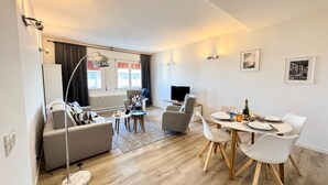 A modern living room with a sofa, TV, and dining area with chairs and a table. - Venezia Dream Stay by Ca-sa Check (Mestre)