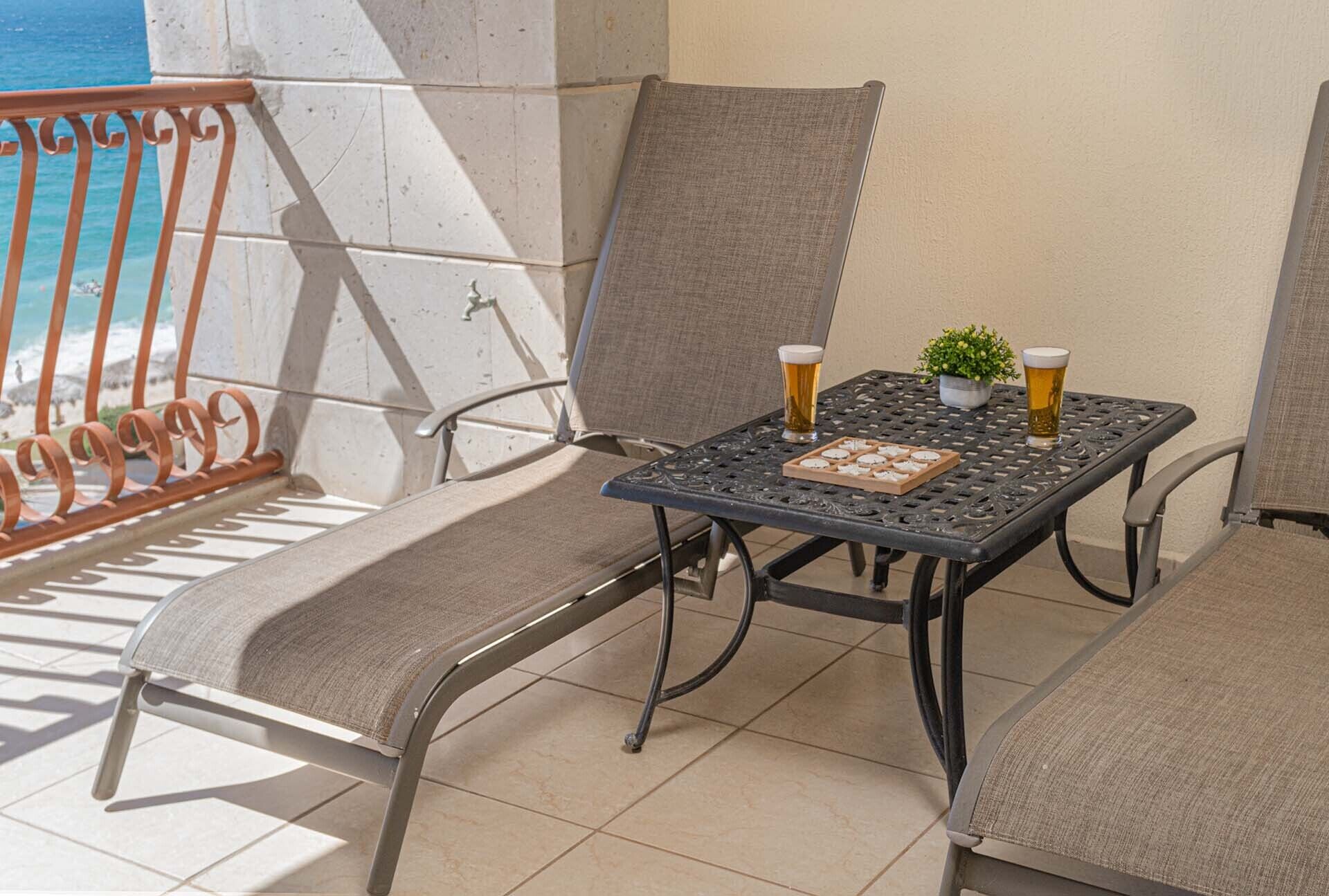 Ein Balkon mit zwei Stühlen, einem Tisch und zwei Biergläsern.