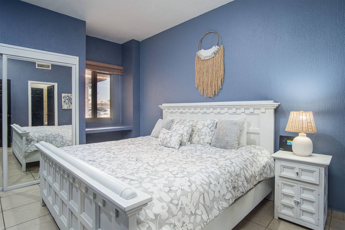 Une chambre à coucher avec un lit, une table de chevet et un miroir.