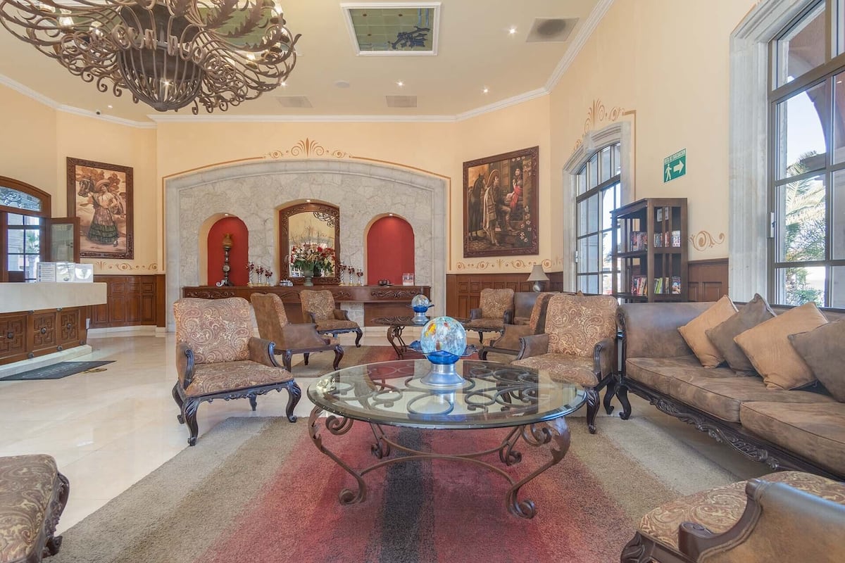 Un hall d’entrée spacieux, agrémenté d’une table basse ronde en verre, de fauteuils décoratifs, d’un canapé et d’un lustre.
