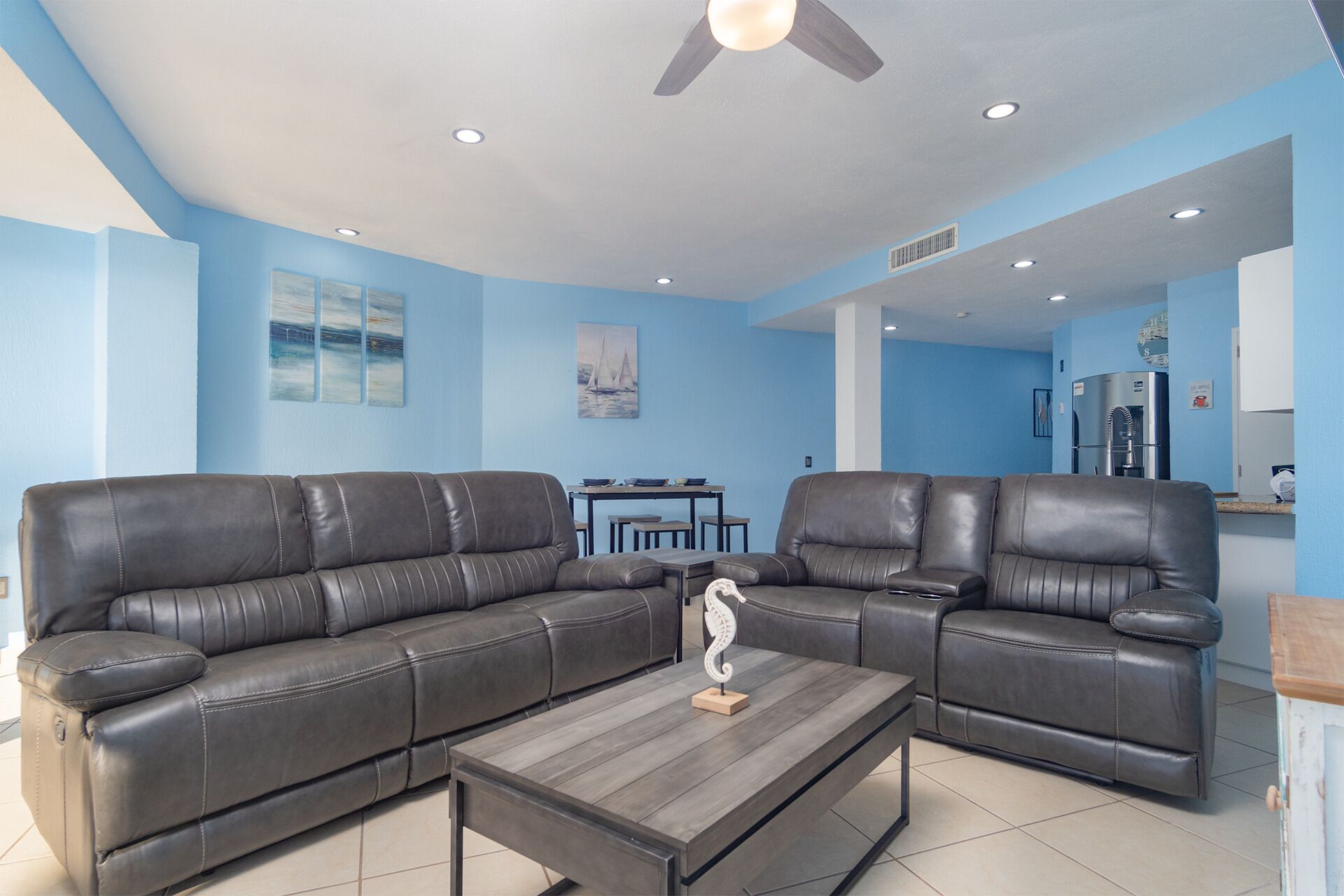A living room with two leather sofas, a coffee table, and a ceiling fan.