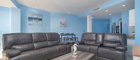 A living room with two leather sofas, a coffee table, and a ceiling fan.