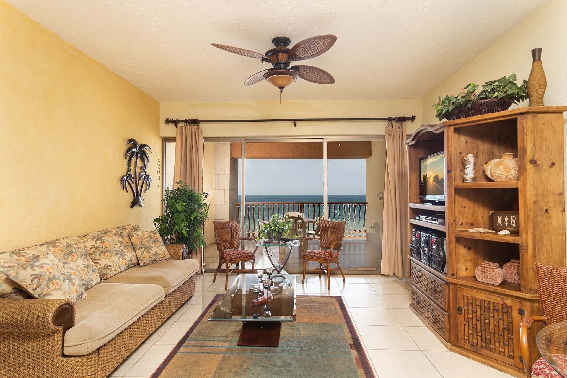 A living room with a sofa, chairs, a coffee table, a TV, and a wooden cabinet with decorative items.