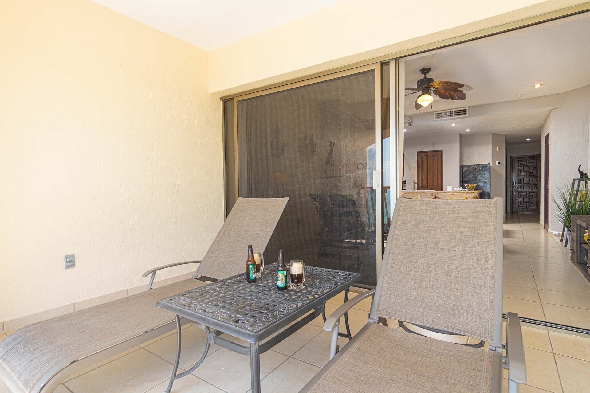En balkon med et bord, stole og en skydedør, der fører til et køkkenområde.