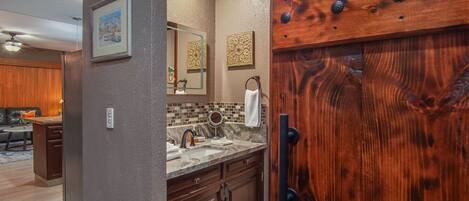 A modern kitchen with a marble countertop, wooden cabinets, and a large wooden door with a metal handle.