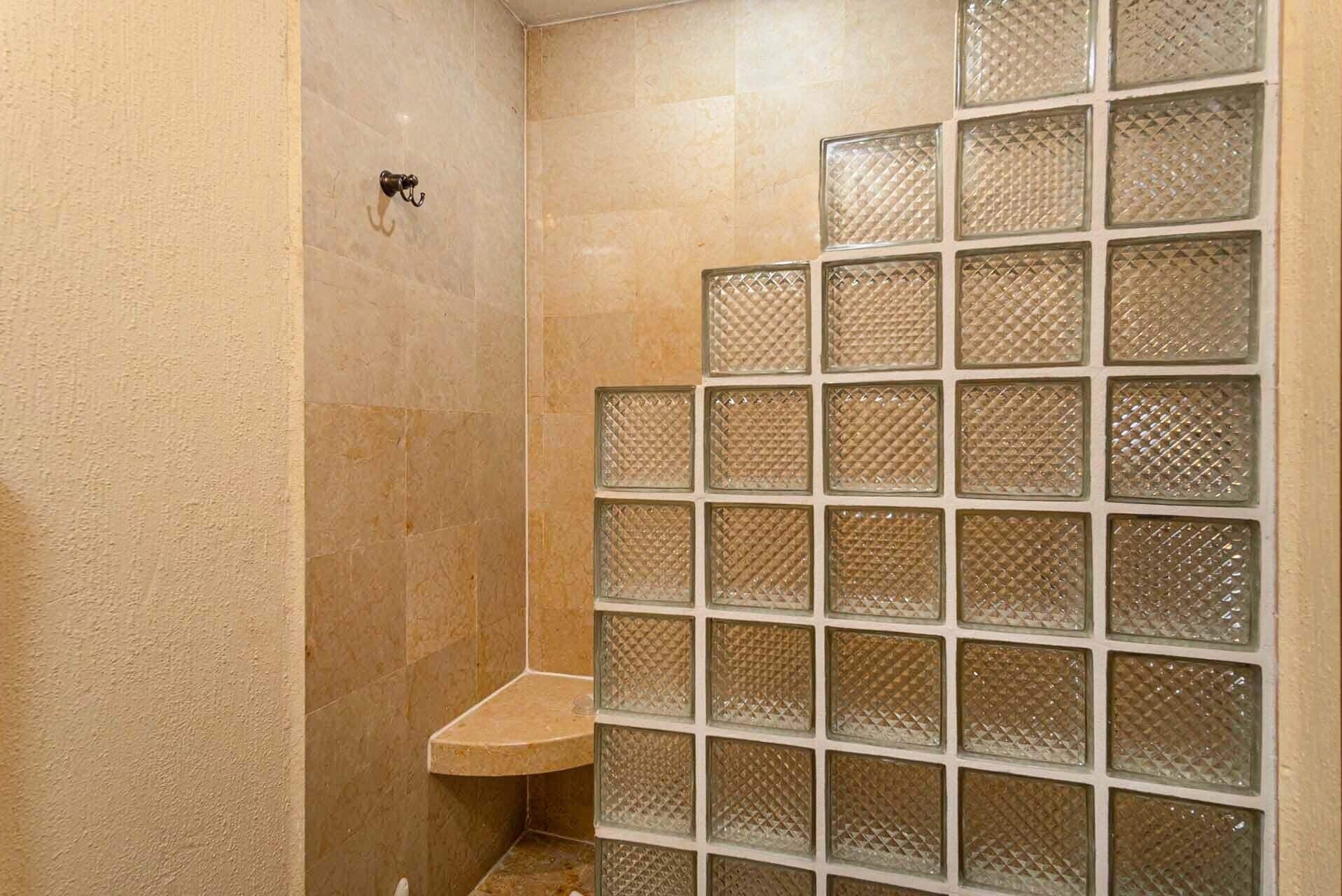 Une salle de bain avec une douche à parois de verre et un petit banc.