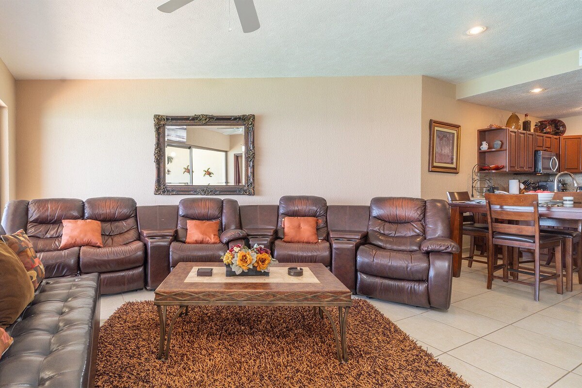 A living room with a sectional sofa, a coffee table, and a fireplace.