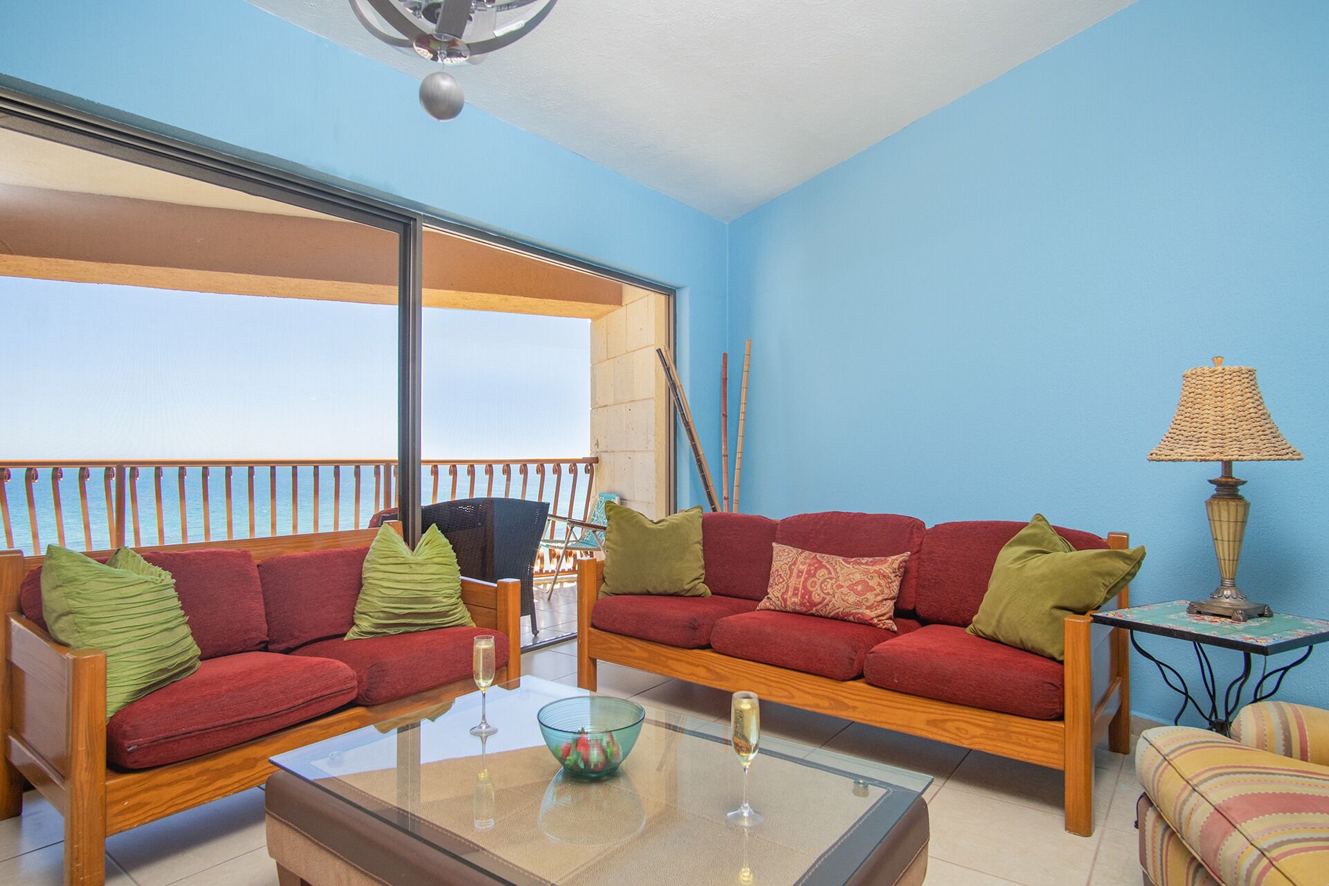 Ein Balkon mit zwei roten Sofas, einem Glastisch und einem kleinen Tisch mit einer Lampe.