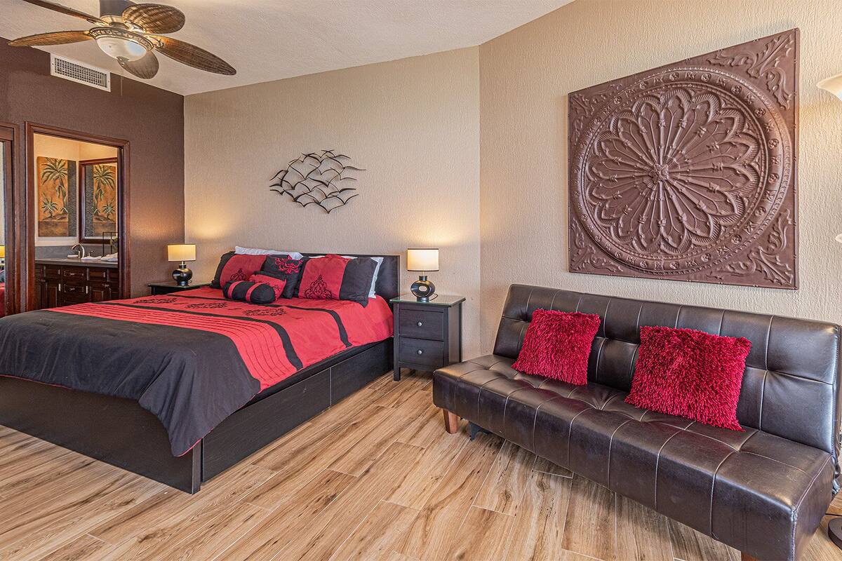 Une chambre à coucher avec un grand lit, un canapé, un ventilateur de plafond et un élément décoratif mural.