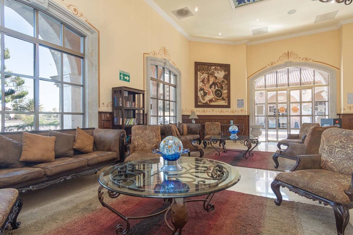 Un hall d’entrée spacieux avec un grand espace salon, une table basse en verre et une bibliothèque.