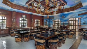 Un restaurant spacieux avec un plafond haut, des poutres en bois et une fresque représentant l’océan.