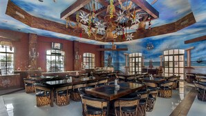 A spacious restaurant with a nautical-themed ceiling, large windows, and a central island with bar stools.