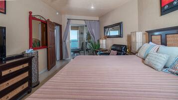 Un dormitorio con una cama grande, un aparador de madera, un televisor y un balcón con vistas.