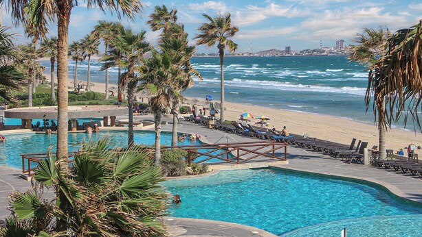 A pool area with a view of the beach and ocean.