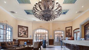A spacious lobby with a grand chandelier, comfortable seating, and large windows allowing natural light.