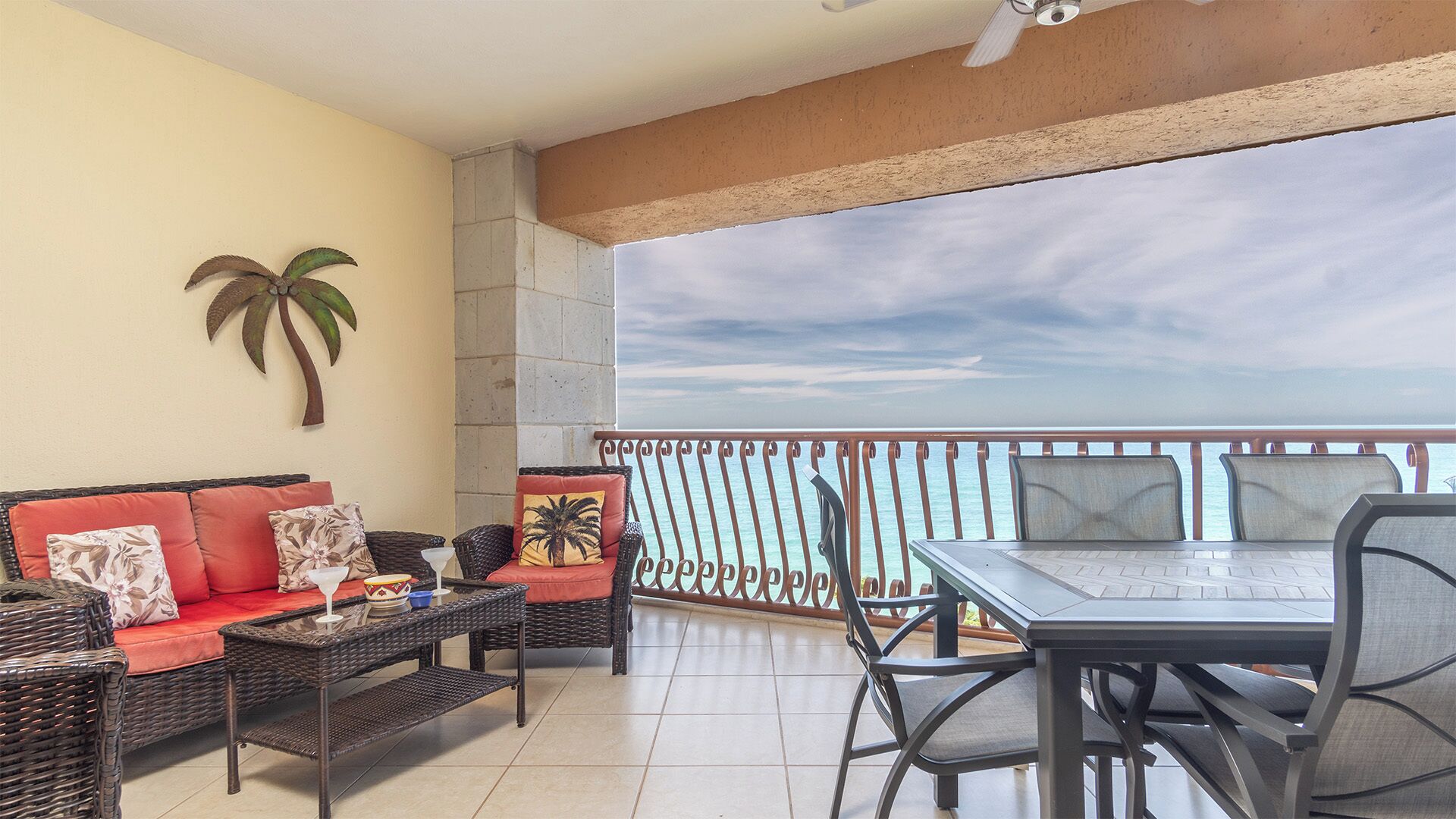 Un balcón con vista al mar, amueblado con un sofá, sillas y una mesa.