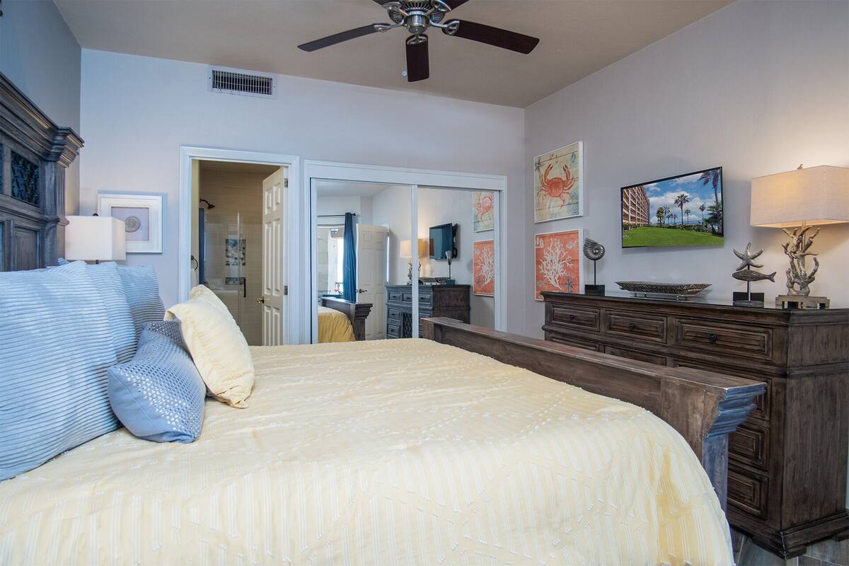 A bedroom with a bed, dresser, and artwork on the walls.