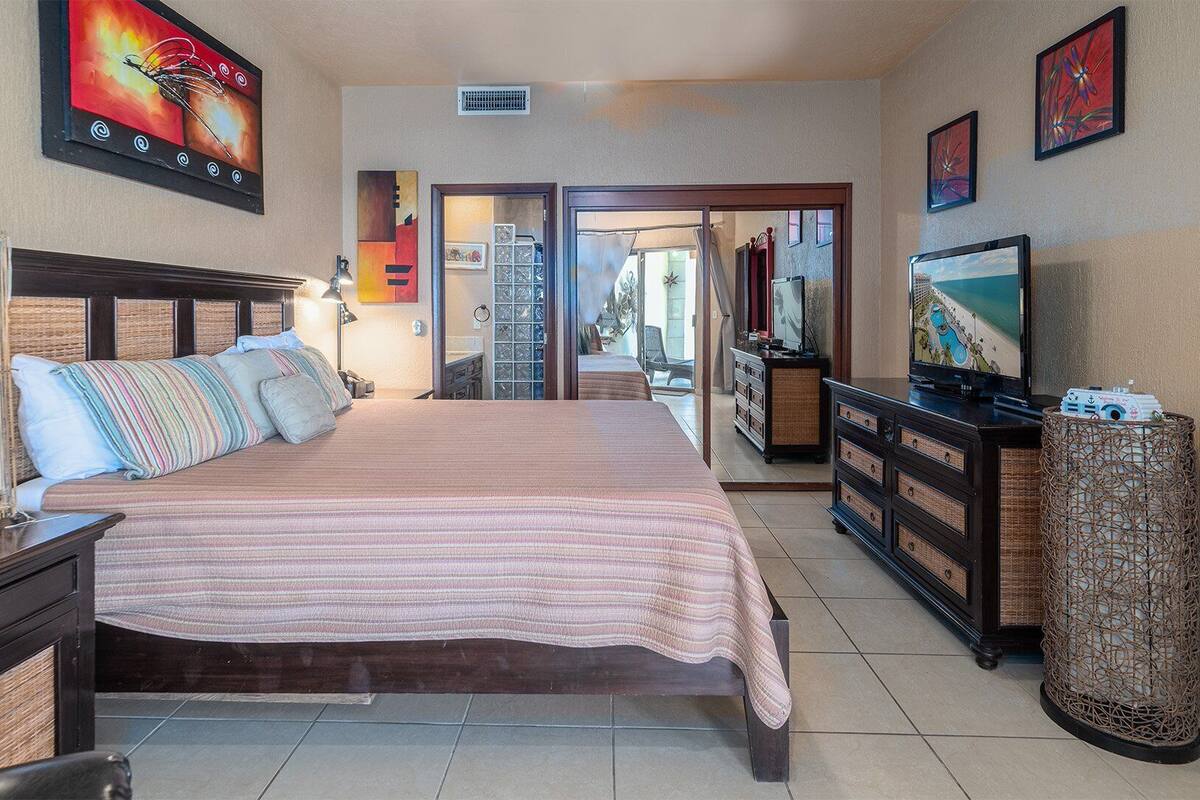 A hotel room with a bed, a dresser, a television, and artwork on the walls.