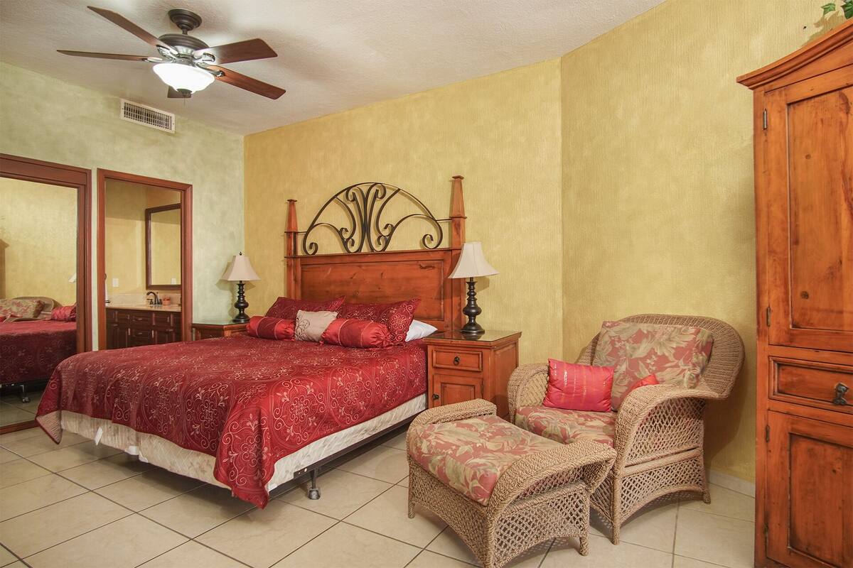 A bedroom with a bed, two bedside tables with lamps, a chair, and a wardrobe.