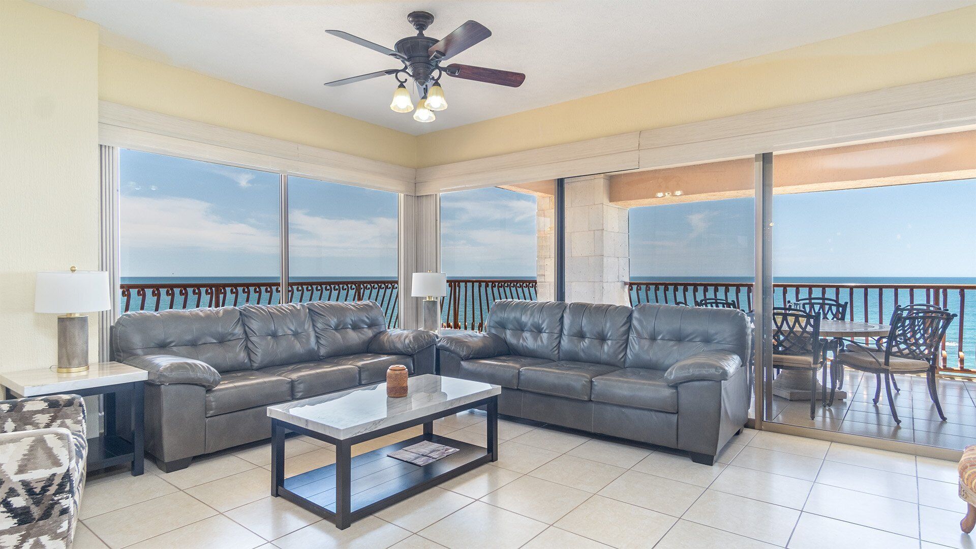 Ein geräumiger Balkon mit Meerblick, eine Sitzecke mit Sofa und Tisch sowie ein Deckenventilator.