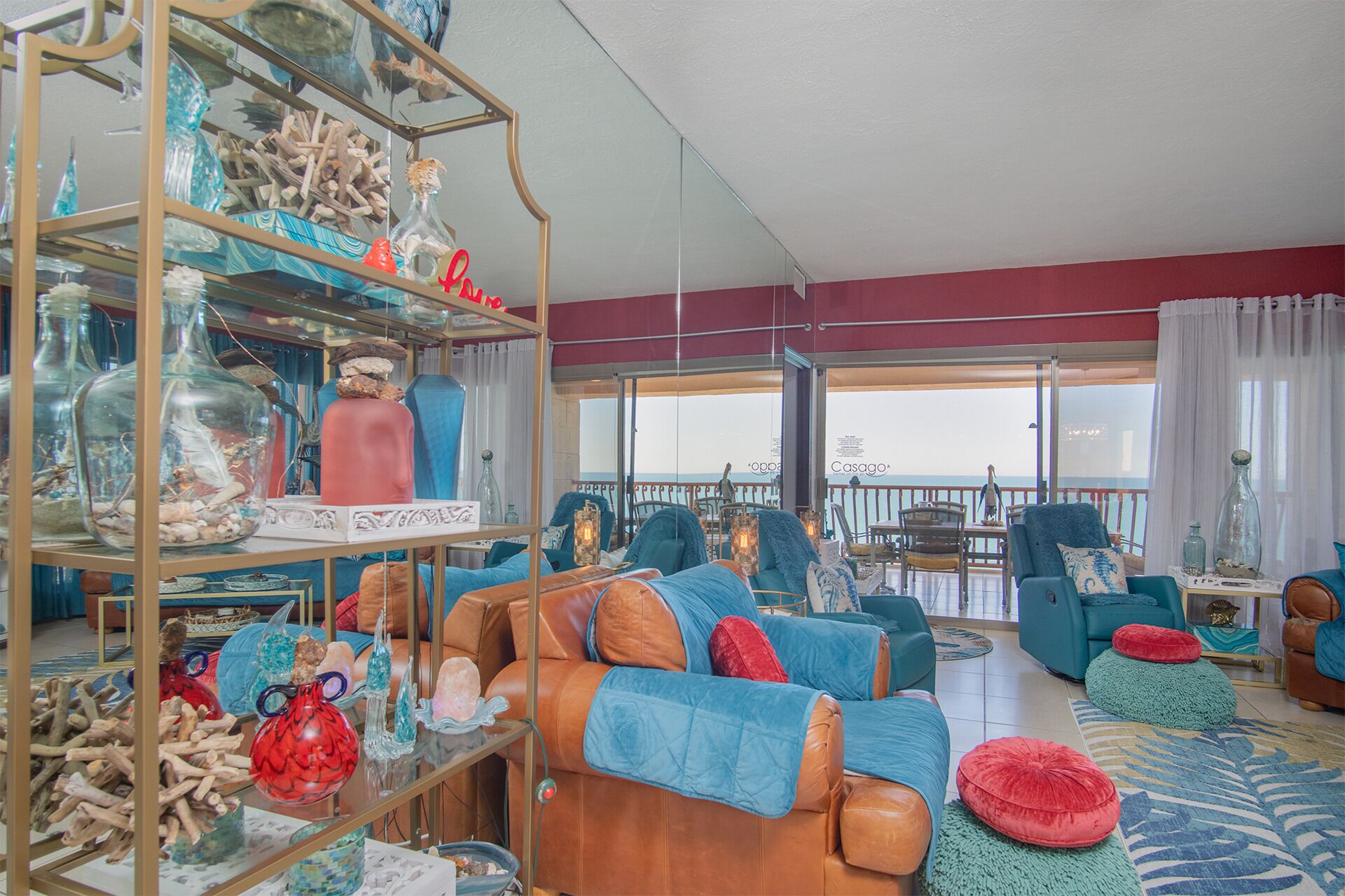 Een ruime woonkamer met leren banken, een glazen vitrine gevuld met decoratieve objecten, en een balkon met uitzicht.