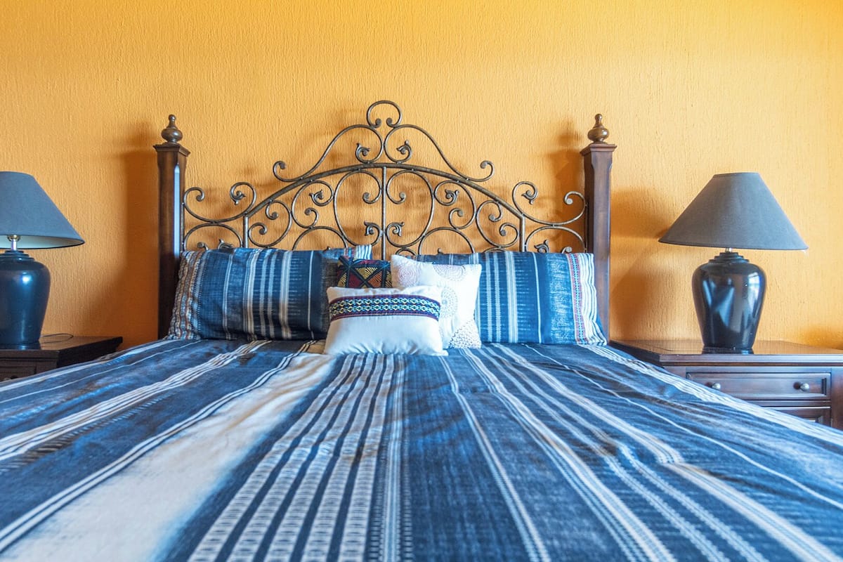 A bed with a striped bedspread, a decorative headboard, and two bedside lamps.