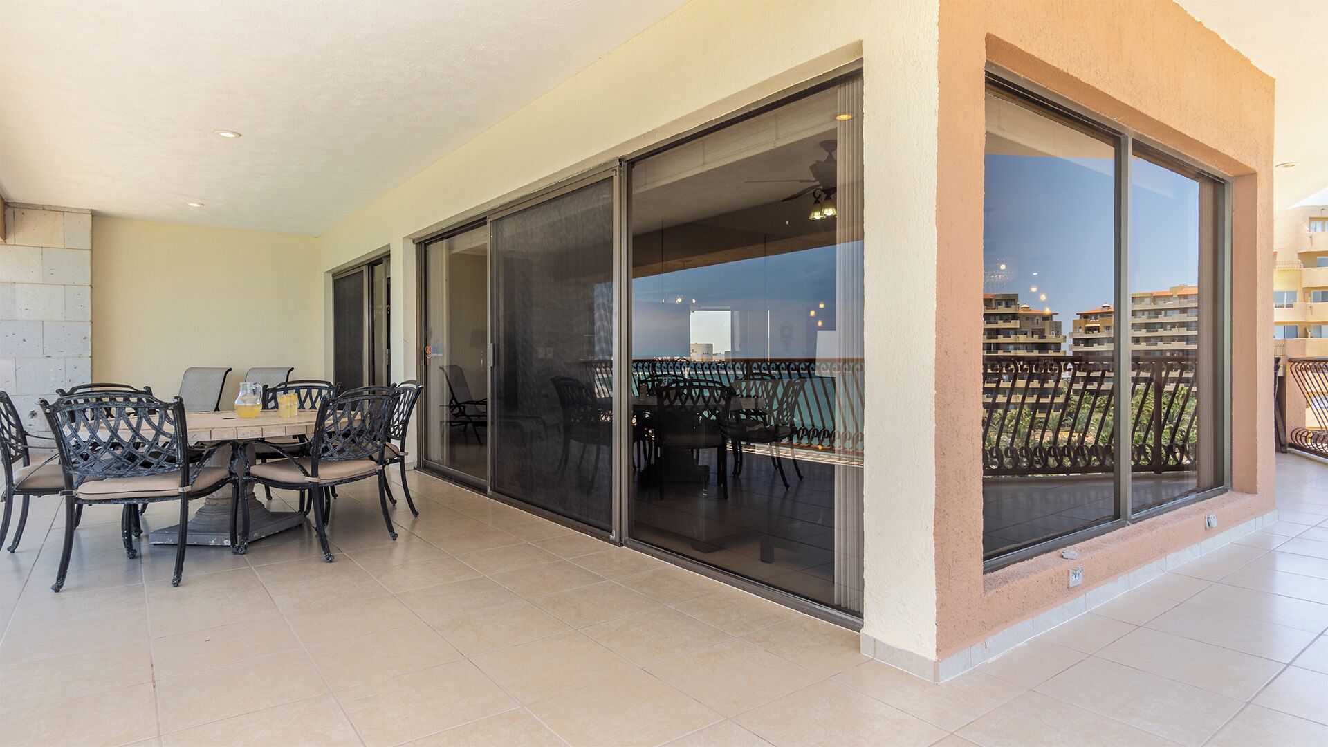A balcony with a dining table and chairs, large sliding glass doors, and a view of the cityscape.